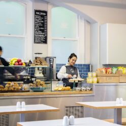 A photo of people restocking the cake stand preparing hot drinks