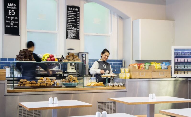 A photo of people restocking the cake stand preparing hot drinks