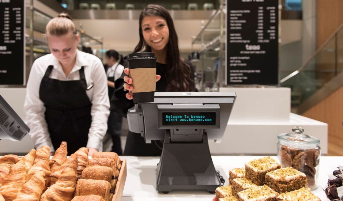 A barista passing a coffee to a customer