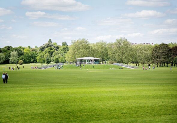 An external photo of the cafe in the park with people sitting on the banks